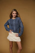 Model wearing the Long Sleeve Cable Knit Crop Sweater in denim blue with a cream skirt